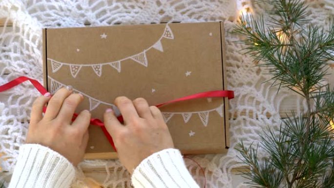 女性双手打开新年礼物的包装-纸板箱中的姜饼饼干