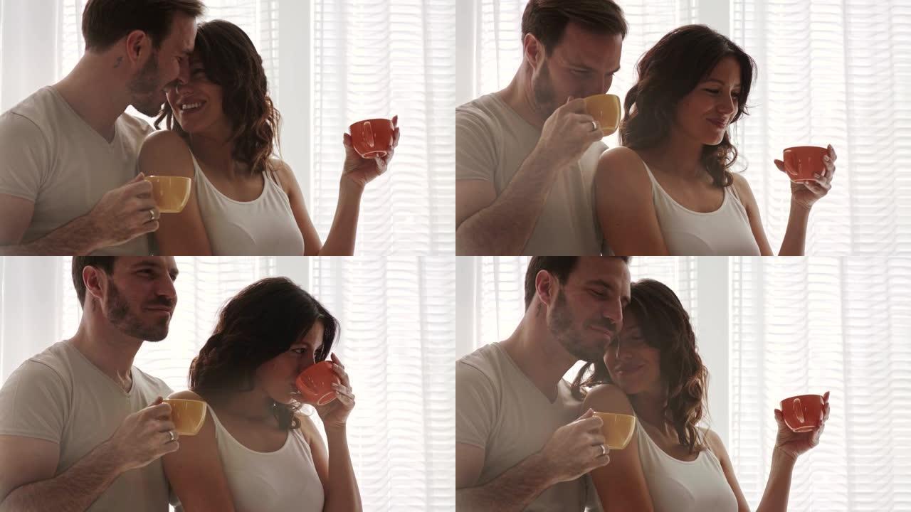 拥抱中的夫妇享受早晨的咖啡，享受片刻的亲密关系