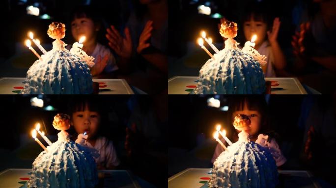 快乐的家庭在家里给小女儿庆祝生日。可爱的小女孩吹生日蛋糕。幸福家庭和童年的概念。