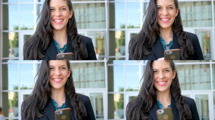 一位穿着考究的女士在她的智能手机上抬头对着镜头微笑