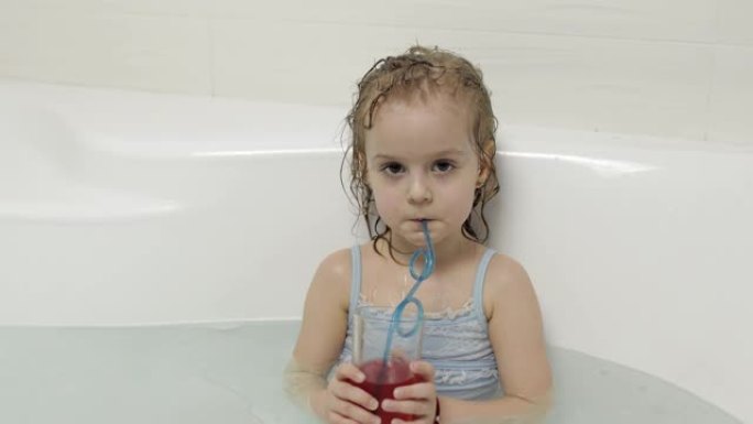可爱的金发女孩穿着泳衣洗澡，喝鸡尾酒。小孩子