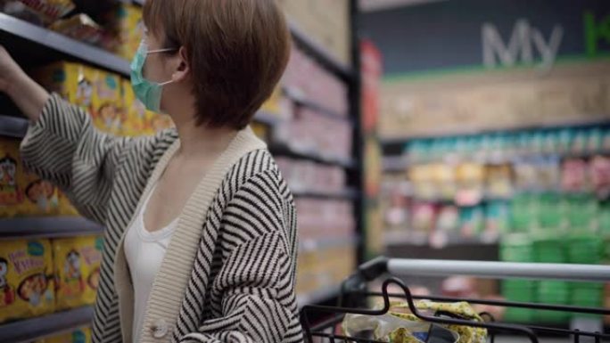 年轻的亚洲妇女戴着口罩，以防止在超市病毒和购买