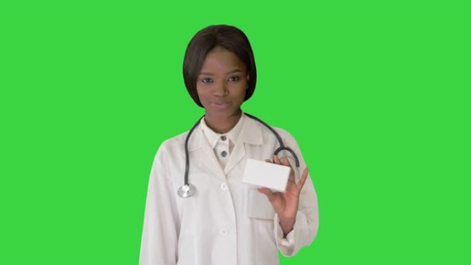 女医生微笑着在绿色屏幕上拿着一盒药物，色度键