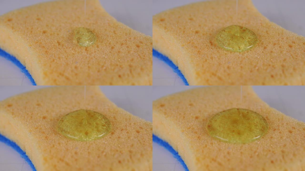 将透明的洗碗凝胶倒在带有蓝色基底特写的黄色多孔海绵上