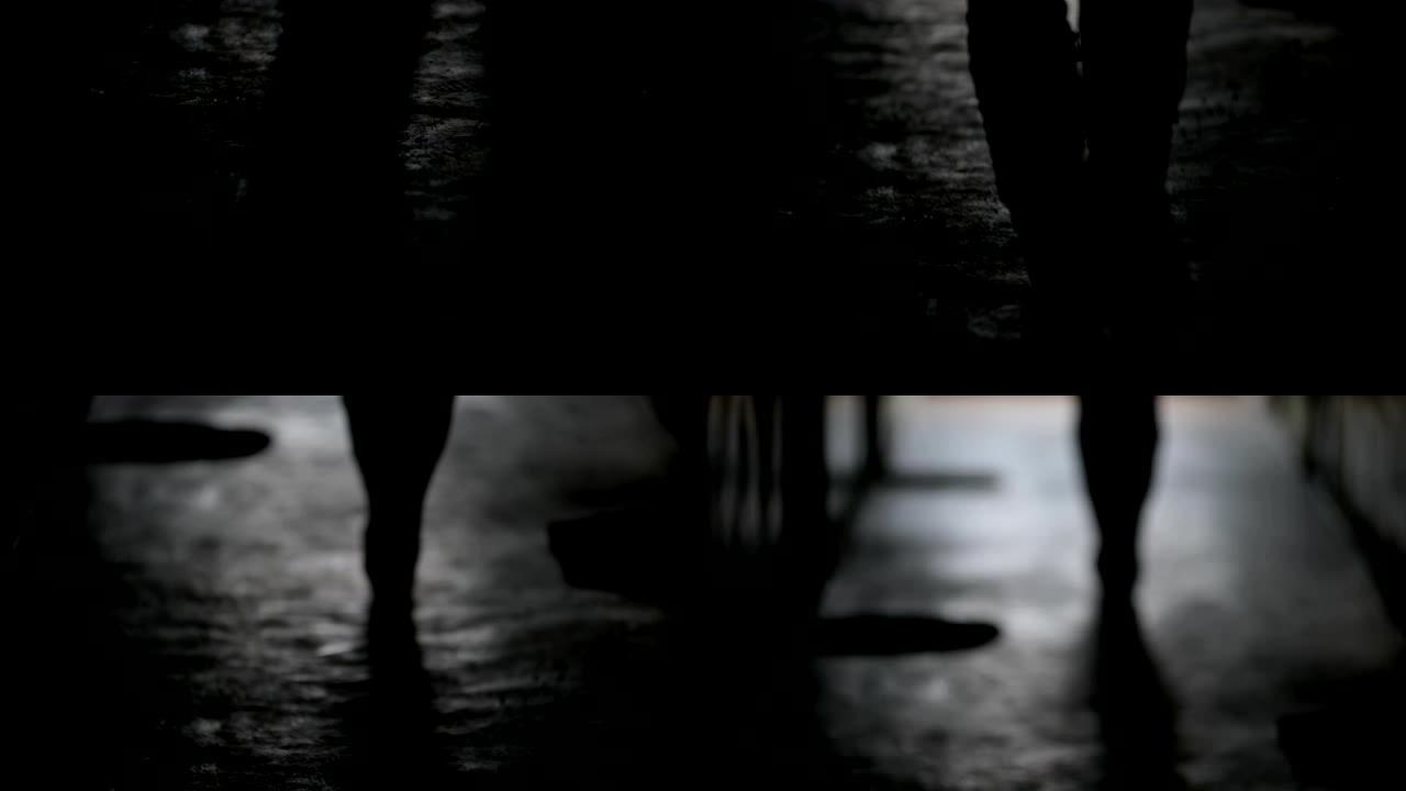 在散焦中从背面观看女性的深色曝光剪影。一个女性人物正沿着黑暗的走廊行走，远离镜头。
