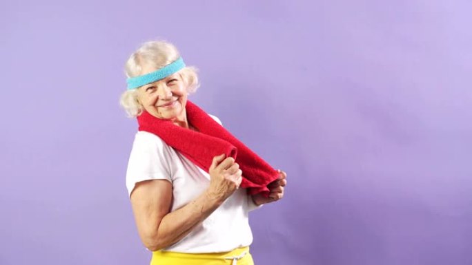 戴着头带和红色毛巾的老年女运动员，看着相机