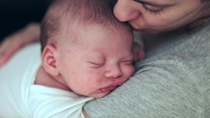 母亲抱着熟睡的新生婴儿亲吻爱的关怀和感情