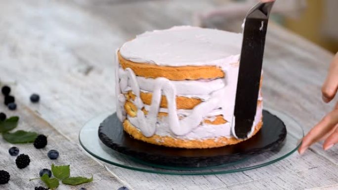 糕点厨师在蛋糕上撒上鲜奶油。