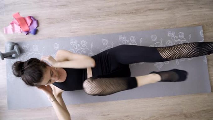 穿着黑色瑜伽裤的女人在瑜伽垫上做嘎吱嘎吱的动作