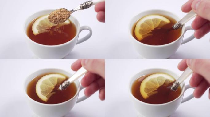 手在装有热红茶的杯子里用甜点勺子添加蔗糖