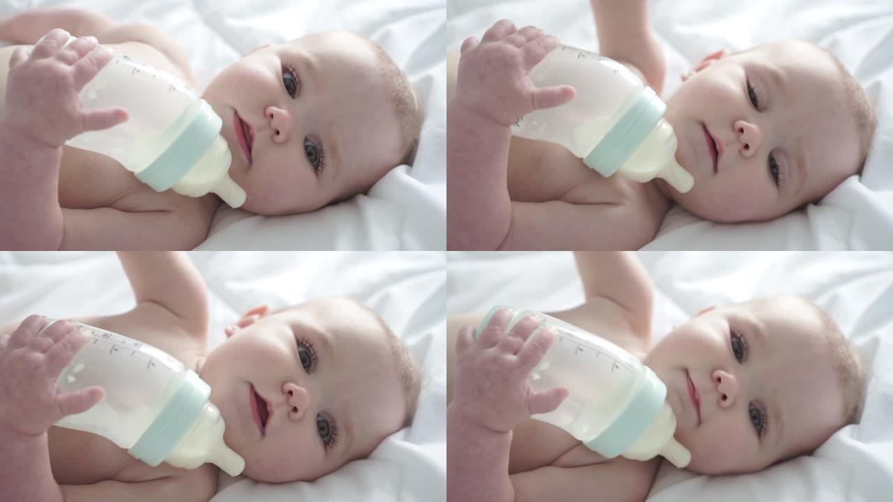 漂亮的女婴躺在床上从瓶子里喝牛奶。儿童在托儿所穿尿布。