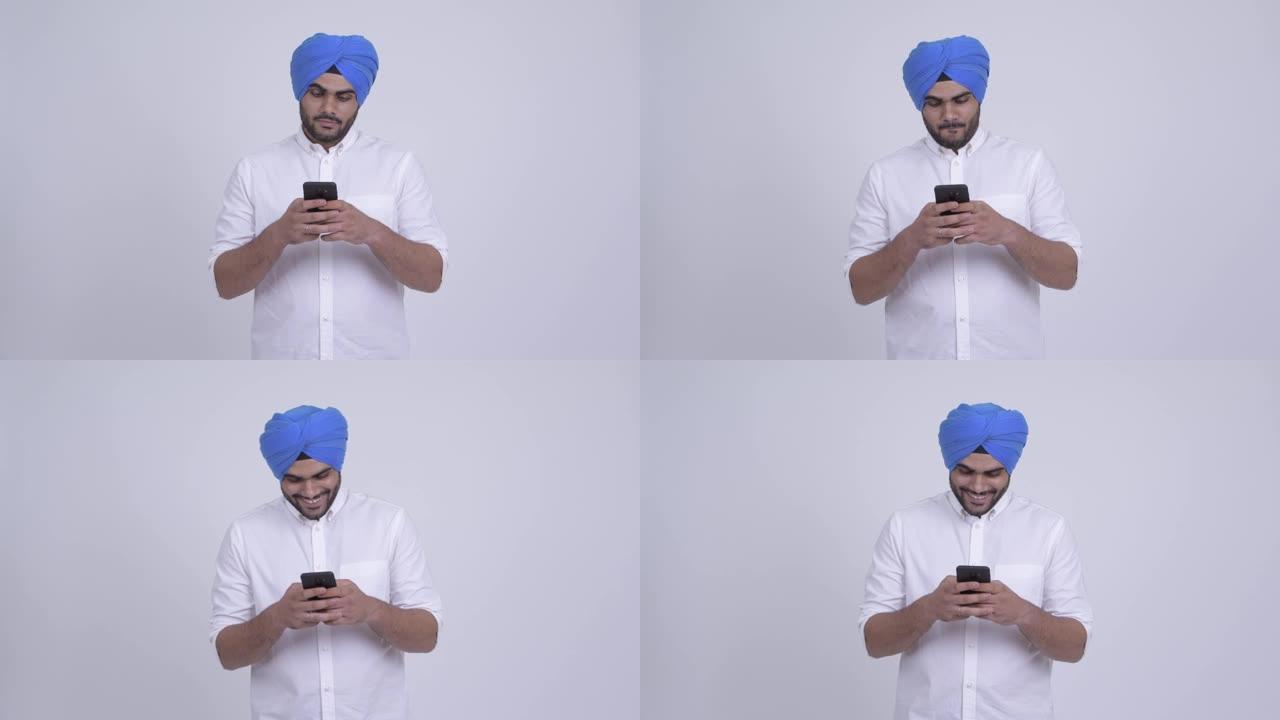 快乐的年轻大胡子印度锡克教男子用手机头巾
