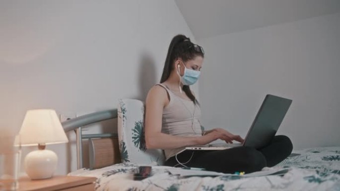 年轻的妇女在检疫的保护面具在家工作在她的床上