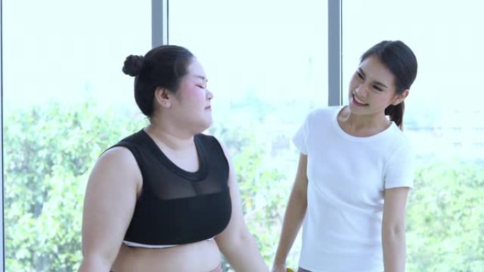 亚洲大型健身女性和教练在健身课上锻炼，教练建议肥胖女性锻炼减肥