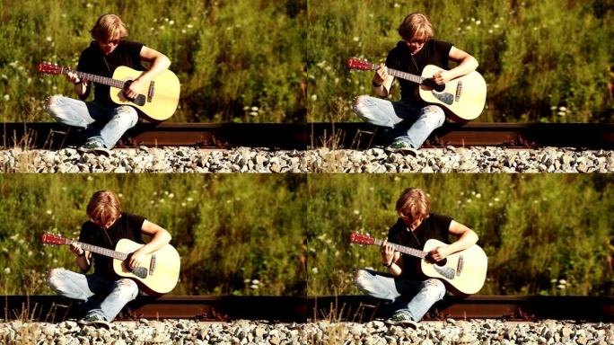坐在铁路上弹吉他的长发少年