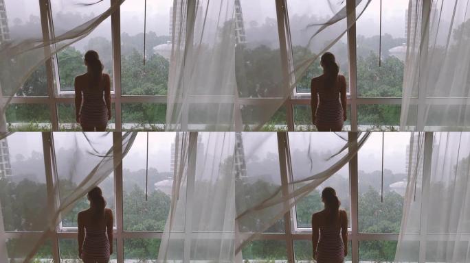 女人在雨中透过窗户看着城市的背景图。