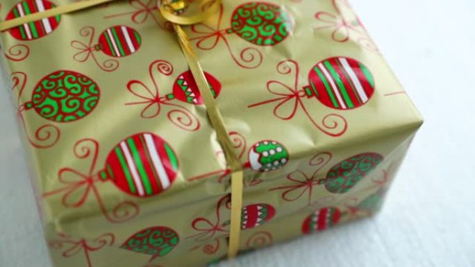 用金箔和纸包装的圣诞礼物角落的特写镜头，圣诞动机和丝带在上面，以120fps的慢动作捕捉。
