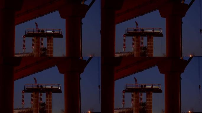 工人的剪影-在立柱上工作的安装人员，正在建造的汽车立交桥的支架