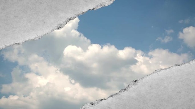 创造性的时间圈视频，在蓝天中快速移动的云，可以通过旧复古垃圾老式纸的边缘撕裂的孔看到。