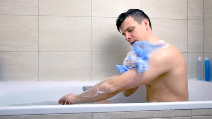 男人坐在浴缸里用沐浴露洗身体。