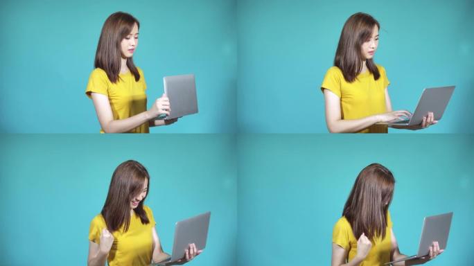 亚洲快乐美丽可爱的年轻女子青少年她拿着笔记本电脑，查看电子邮件后兴奋地庆祝，看着工作室里的相机，孤立