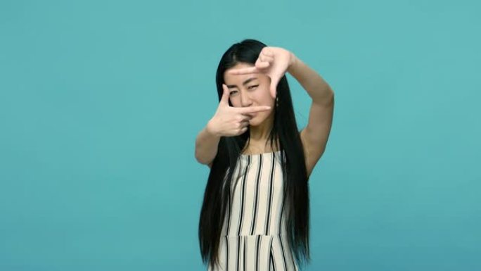 捕捉瞬间。亚洲女性长直黑发透过手指制成的相框形状