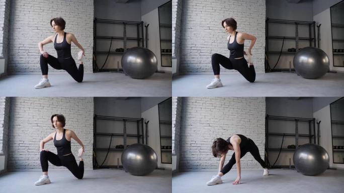 瑜伽垫年轻的运动女子在健身房室内伸展臀部，绳肌，腿部肌肉。伸展运动