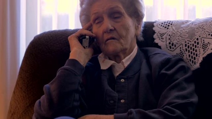 一位双目失明的老年妇女在她的家中收听一个看起来很严肃的4k多莉手机
