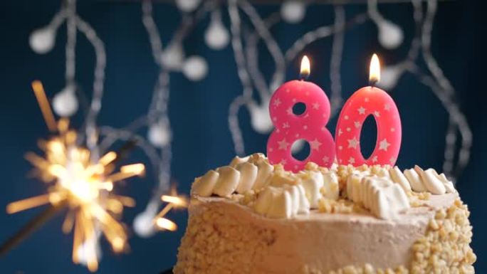 生日蛋糕，蓝色背景上有80号粉色蜡烛和烟火。慢动作和特写视图