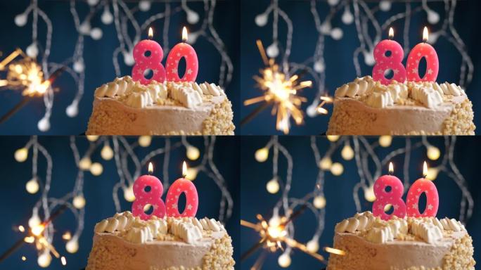 生日蛋糕，蓝色背景上有80号粉色蜡烛和烟火。慢动作和特写视图