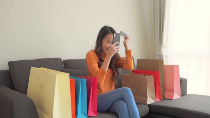 年轻的亚洲女性使用笔记本电脑或手机和信用卡在线购物