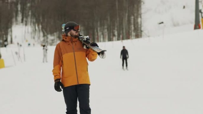 职业运动员站在小山上，看着远处，手里拿着滑雪板。冬季运动。股票视频