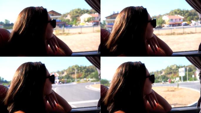 戴着太阳镜的年轻黑发女郎的简介在阳光明媚的日子乘公共汽车旅行，看着窗户。女性乘客在公路旅行中欣赏环境