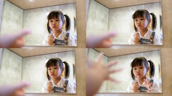 可爱的孩子小女孩化妆，在房间的镜子前涂口红。