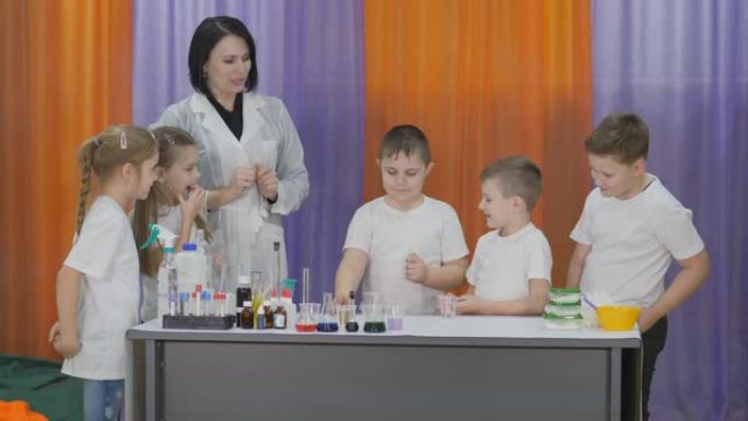 儿童化学实验。男孩将试剂从试管中倒入塑料杯中进行化学实验。儿童有趣的实验。一名妇女进行认知科学课程。
