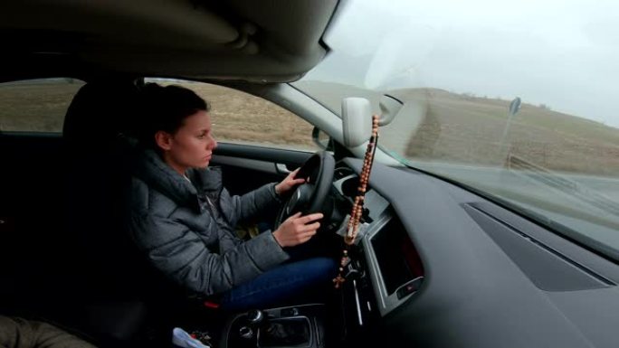 在开车去旅行的过程中，年轻女性开着车，带着高兴的积极表情开心地微笑