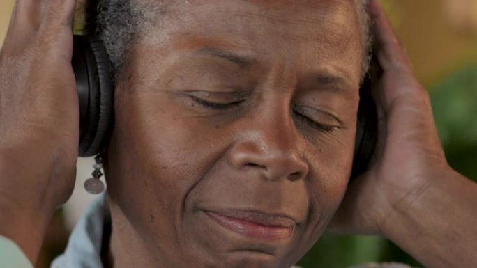 美丽的黑人高级女性戴上耳机享受她的音乐
