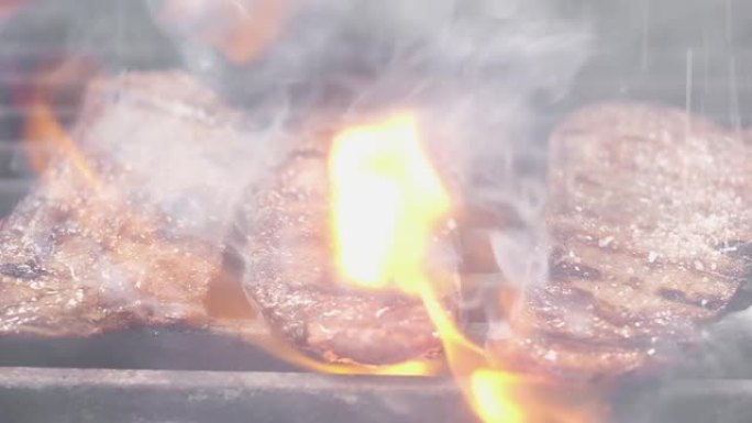 库克在牛排上撒盐。烤架上有三块新鲜的油炸牛排。肉是用火准备的。主厨盐牛肉里脊肉。特写。