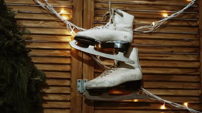 旧的和磨损的花样滑冰溜冰鞋挂在有照明的墙上。冬季运动和爱好