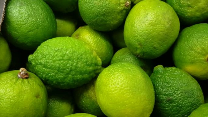 绿色蔬菜柜台上明亮的整个绿色酸橙的特写镜头，4k视频，慢动作，有机水果背景。