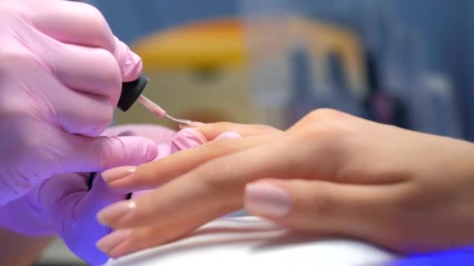 美甲师大师正在画客户的指甲虫胶，手特写。