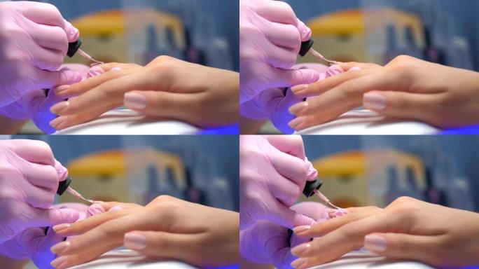 美甲师大师正在画客户的指甲虫胶，手特写。