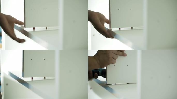 木匠和修理工用电动螺丝刀拧紧并安装胶合板的特写手，以制作橱柜和桌子。