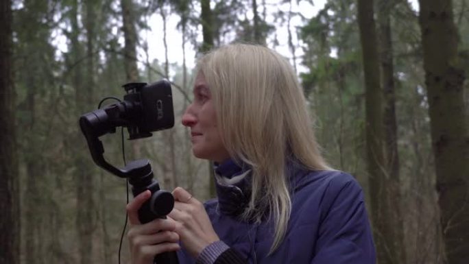 女人博主哭泣，用手机和云台制作视频，森林自然。