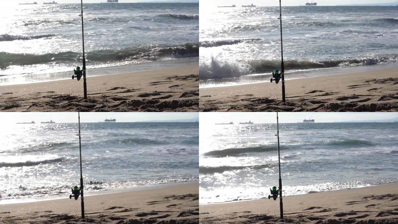 钓鱼竿和渔线轮站在沙滩上的沙滩上，在黄昏时捕捉海鱼