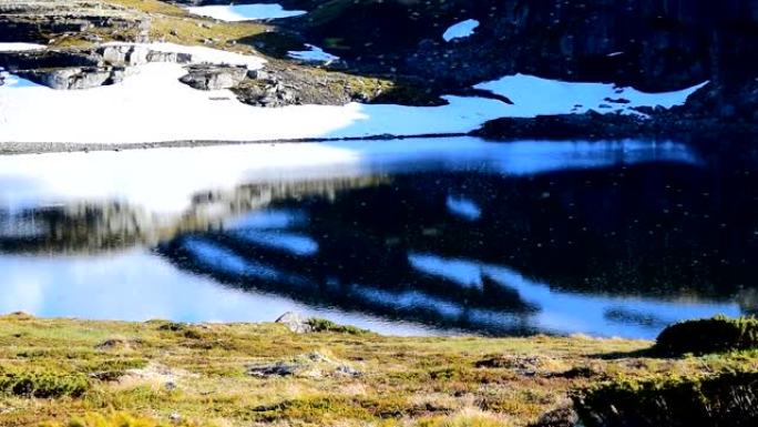 许多蚊子在雪路Aurlandsvegen附近的山湖上空飞行。慢动作视频。挪威。