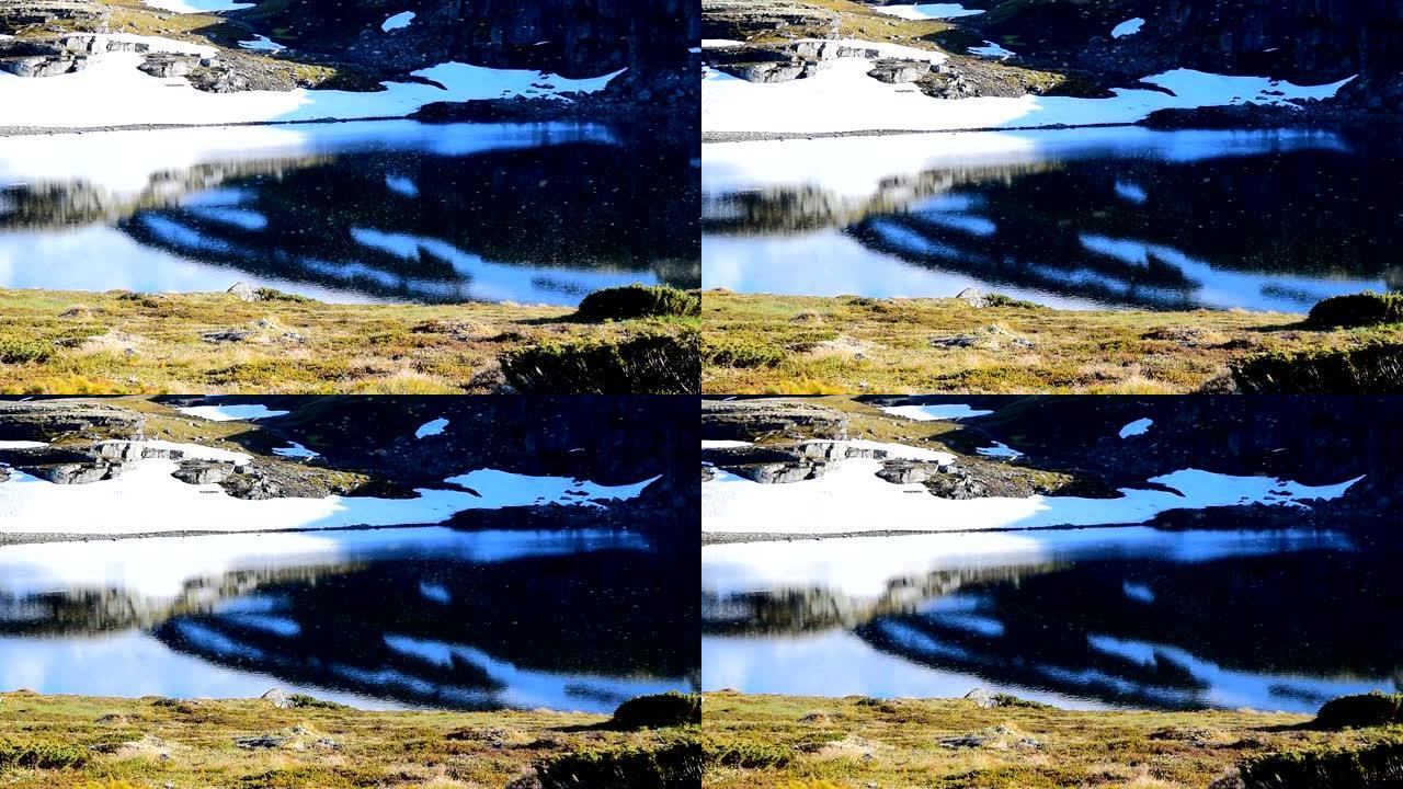 许多蚊子在雪路Aurlandsvegen附近的山湖上空飞行。慢动作视频。挪威。