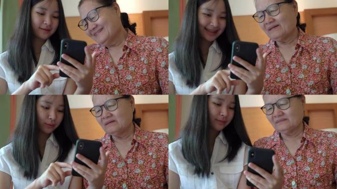 亚洲漂亮的侄女教她的祖母使用智能手机和新技术感到幸福和微笑，家庭观念