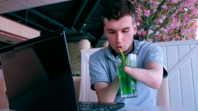 残障的残疾人用笔记本电脑在咖啡馆里工作喝鸡尾酒。