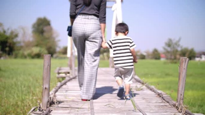 SLO MO，母亲与儿子牵手，走在竹桥上